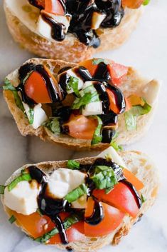 three pieces of bread with different toppings on them sitting on a marble counter top