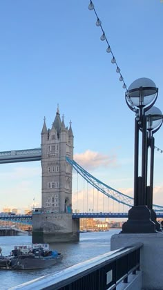 there is a tower bridge that has lights on the side of it and boats in the water below