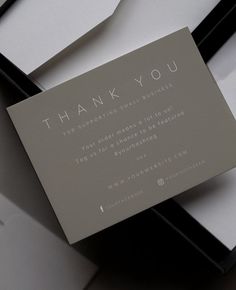 a thank you card sitting on top of a white and black box with the words thank you