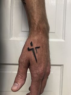 a man's hand with a cross tattoo on it