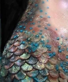 the back of a woman's body covered in blue and pink shells