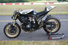 a black and gold motorcycle parked on top of a parking lot next to a fence