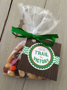 a bag filled with lots of candy sitting on top of a wooden table next to a green ribbon