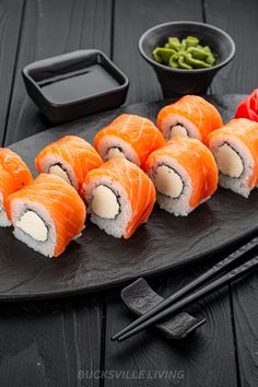 sushi on a black plate with chopsticks next to it