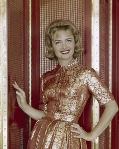 a woman standing in front of a red door with her hands on her hips and smiling at the camera