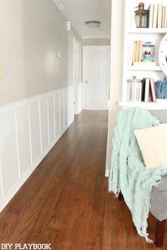 a living room with hard wood flooring and white bookcases filled with books