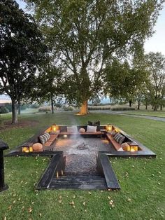 an outdoor fire pit in the middle of a grassy area with couches on it