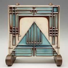 an art deco tile sculpture with wooden wheels and handles in blue, brown and white