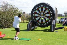 the man is practicing his golf skills on the course in front of an enormous dart