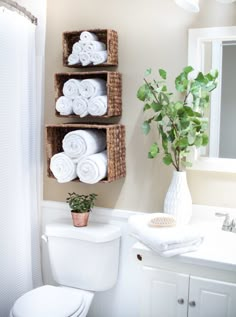 a white toilet sitting next to a bathroom sink under a window with towels on it