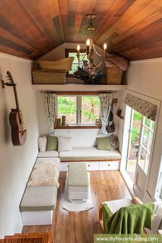 the interior of a tiny home with wood flooring and white furniture, including a couch