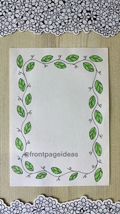 a piece of paper with green leaves and flowers on it, in front of a lace border