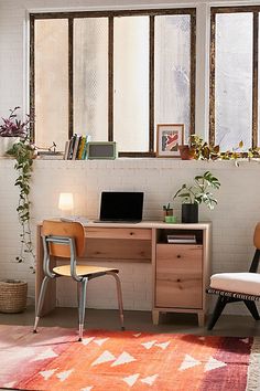 a desk with a laptop on top of it next to a chair and potted plants