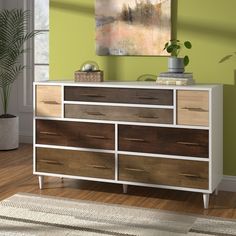 a white and brown dresser sitting on top of a hard wood floor next to a green wall