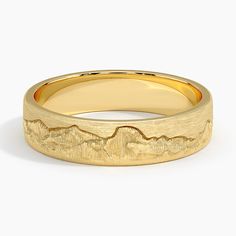 a yellow gold wedding band with mountains in the background and a mountain range engraved on it