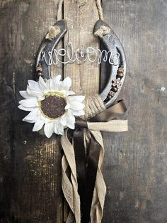 a sunflower is placed on the front door of a rustic wooden door that says welcome