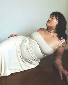 a woman laying on the floor wearing a white dress