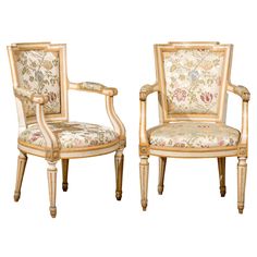 a pair of chairs with floral upholstered back and arm rests against each other