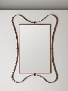 a mirror hanging on the wall next to a metal frame with a cord in front of it