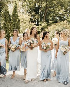 a group of women standing next to each other holding bouquets in their hands and smiling