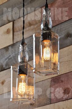 two hanging lights made out of glass jars on a wooden wall with wood planks in the background