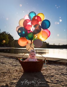 a baby is sitting in a basket with balloons