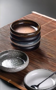 two bowls with spoons are sitting on a mat