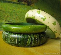 three green and white vases sitting on top of a wooden table next to each other