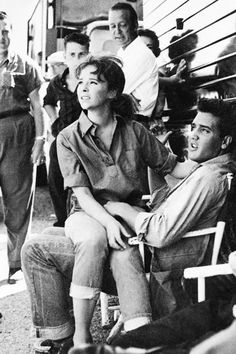 a black and white photo of people sitting on chairs in front of a bus with their eyes closed