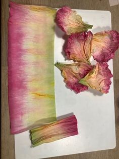 some flowers are sitting on a table next to a piece of paper that has been dyed pink and green