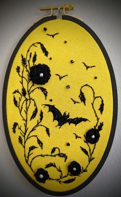 a yellow wall hanging with black flowers and bats