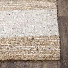 an area rug with white and beige stripes on the floor in front of a wooden floor