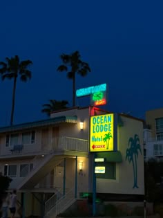 the ocean tower hotel is lit up at night with palm trees and people walking by