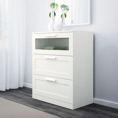 a white dresser with two vases on top of it