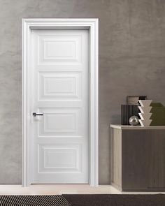 a white door in a room next to a rug and table with vases on it