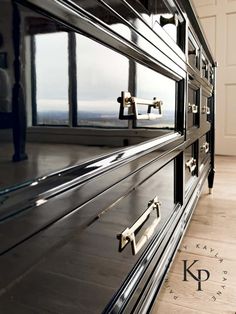 a large black cabinet with two handles on it's sides in front of a window