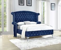 a bed with blue velvet upholstered headboard and foot board in a bedroom