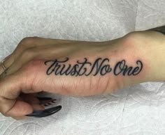 a person's hand with a tattoo that says trust no one