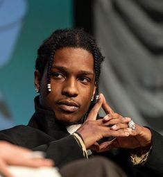 a man with dreadlocks sitting down and talking on a cell phone in front of him