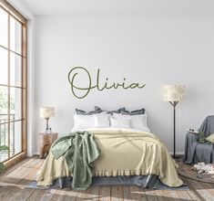 a bedroom with white walls and wooden flooring has a green name on the wall