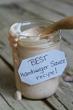 a jar filled with sauce sitting on top of a wooden table next to a spoon