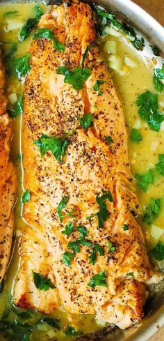 two fish fillets in a pan with broth and parsley on the side