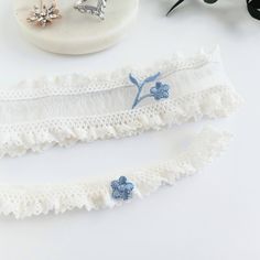 Beautiful white Wedding garters made with elastic lace and tiny blue embroidered flowers. Custom sized just for you and comes in a gift box. The keepsake garter measures 1 5"8" wide and the toss 5/8".  MEASURING INSTRUCTIONS: Use a soft tape measure or string and ruler. Measure where you want to wear your keepsake (the larger) garter. Measure a bit snug, not too tight or too loose. Order your actual measurement and I will take some off so it stretches to fit. The toss garter will be made smaller than the keepsake. SHIPPING: Each item is custom handmade to order and will ship out 3-5 business days after you order. Then shipping takes another 2-5 days. Most orders in the USA arrive 8-10 days after the order date, but allow up to 2 weeks. If you need it sooner than 2 weeks, add the rush fee s Wedding Garter Blue, Blue White Weddings, White Garters, Blue Garter, Flower Girl Accessories, Something Blue Wedding, Wedding Garters, Wedding Moodboard, Bridal Garter