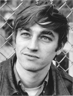 a black and white photo of a man in front of a fence with his eyes wide open