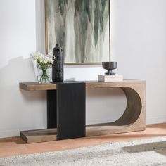 a vase with flowers sitting on top of a wooden table next to a black vase