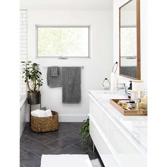 a white bathroom with two sinks and a bathtub next to a window in the ceiling