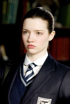 a woman in a suit and tie is posing for a photo with bookshelves behind her