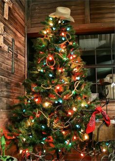 a decorated christmas tree with lights and presents under it in front of a wooden wall