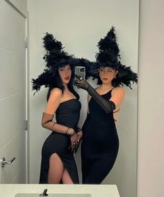 two women dressed in black are taking a selfie in the bathroom with their hats on