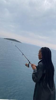 a woman standing on the edge of a pier holding a fishing rod